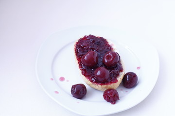 half bun with cherry jelly on a white plate, isolated