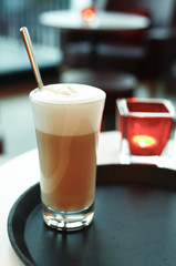 A glass latte macchiato in the cafe, the background with sharpening depth