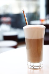 A glass latte macchiato in the cafe, the background with sharpening depth