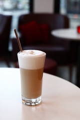 A glass latte macchiato in the cafe, the background with sharpening depth