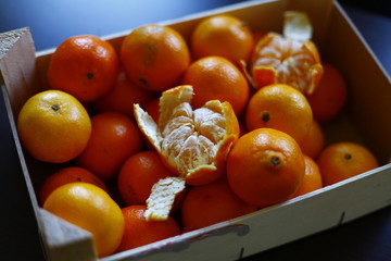 close up of tangerine and citrus fruits in a wooden box on a table