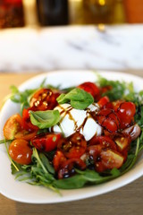 tomato mozzarella salad served in a white plate with oil, balsamic and basil leaves