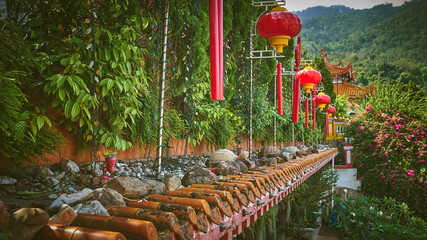 Red chinese lanterns hanging in the green garden of a buddhist temple