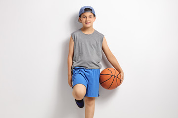 Boy with basketball leaning against a wall