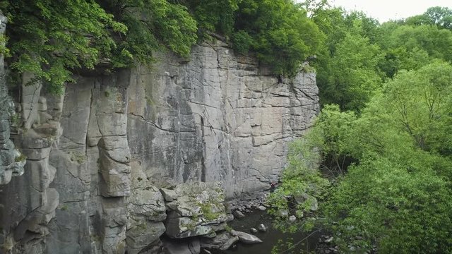 Aerial footage. Fly in canyon. Zoom in climber on rock wall
