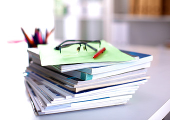 A stack of documentation is on the desktop in the office