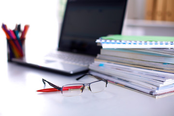 A stack of documentation is on the desktop in the office