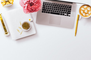 A feminine desktop flatlay hero image, with a macbook laptop, pink peony, white planner, and gold...