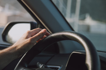 Young man hand holding the car steering wheel