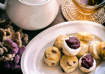 Homemade raisin scones served with homemade strawberries jam,clotted cream and tea.Scones is English pastry for afternoon tea,cream tea. Delicious scones Devon shire or Cornish cream style. 