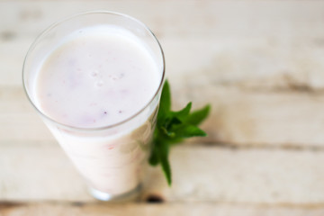 Milk shake yogurt with strawberry slices on a wooden background.