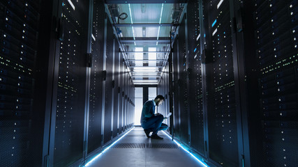 IT Technician Works on Laptop in Big Data Center full of Rack Servers.