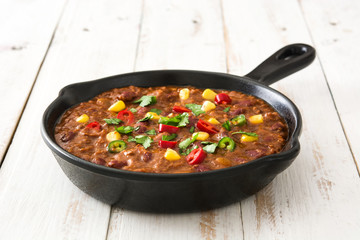 Traditional mexican tex mex chili con carne in a frying pan on white wooden table
