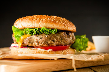 American hamburger with beef on dark background. American tasty food