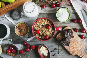 Rural breakfast with cereal, milk, brownie, fresh berries and cottage cheese on a wooden background, top view, flat