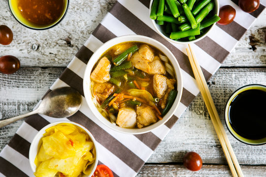 Chinese spicy soup with chicken and noodles, Asian dinner on a wooden background, top view, flat