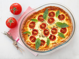 Quiche Lorraine. Traditional French savory pie. Whole tart with cherry tomato and leek. Top view.
