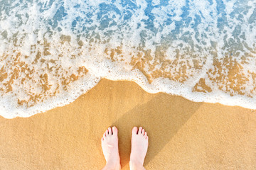 Woman's feet on yellow beach sand
