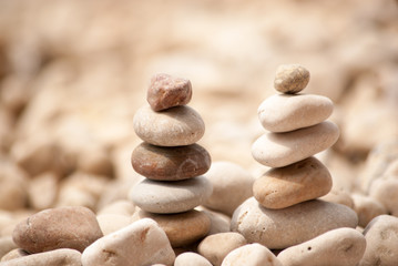 Fototapeta na wymiar Horizontal image of two small zen pagodas of five pebbles against a blurred background of pebble beach 