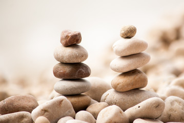 Fototapeta na wymiar Horizontal image of two small zen pagodas of five pebbles against a blurred background of sea and pebble beach 