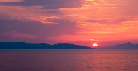 Obraz premium Panoramic image of sunset over the sea with lilac and pink hues in the cloudy sky 