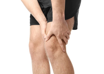 Young man suffering from pain in leg on white background, closeup