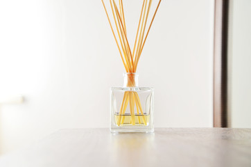 Air refresher with sticks and golden liquid in bright room and white background, close up