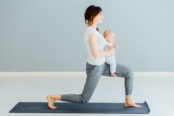 young mother does physical yoga exercises together with her baby