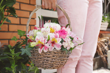 Fototapeta na wymiar Woman holding basket with beautiful blooming flowers