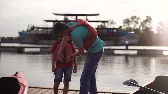 The father zip a life jacket, to the son to swim on a kayak