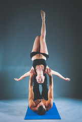 Young couple practicing acro yoga on mat in studio together. Acr