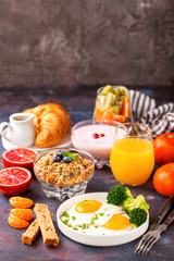 Breakfast - fried eggs with broccoli, muesli, croissant and juice on a table. Selective focus. Copy space