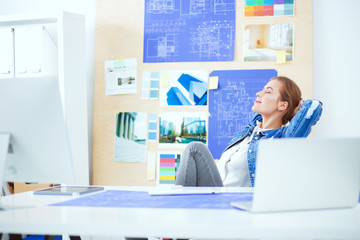 Two young woman standing near desk with instruments, plan and la