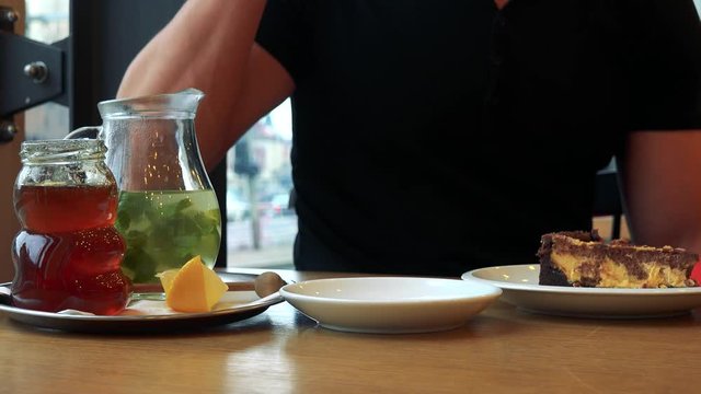 A man sits down to a table with meal in a cafe and takes a sip of tea - closeup on the table