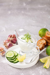 Tzatziki sauce in a glass sauce-boat. Ingredients for a dzadziki. Turkish dish cacik. Selective focus. Copy space