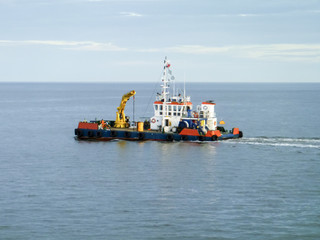 Fototapeta premium A small service ship in a cargo industrial port. A ship in the sea