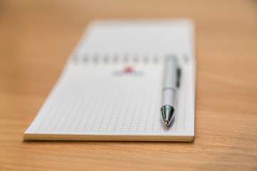 A notebook and ballpoint pen lying on a wooden table.