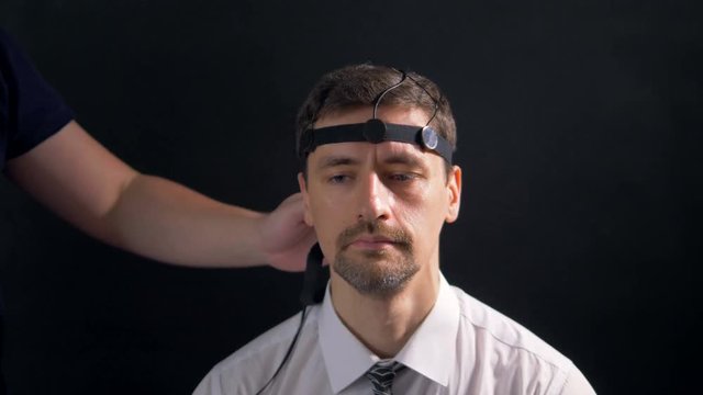 A man being fitted with polygraph head sensors.