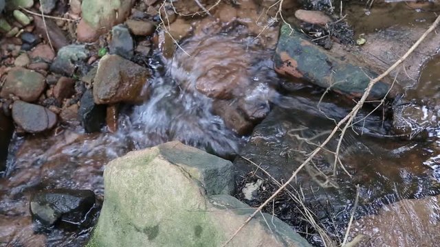 Wasser in einem Bach sprudelt &uuml;ber Steine in einem Kurzfilm