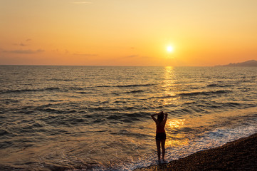Girl silhouette on the sunset sea background. Romantic scene. 