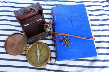 un livre de bord avec une boussole et un coffre de pirate sur fond marin
