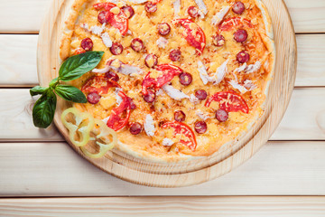 Pizza with salami on the wooden background