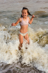 ребенок в волнах прыгает и радуется