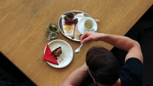 A man sits at a table in a cafe and enjoys pie with tea - top view