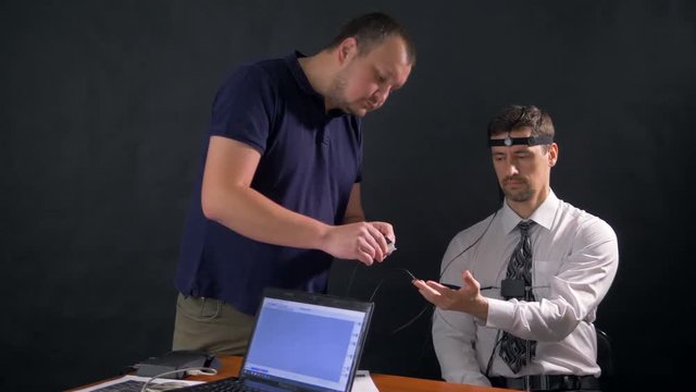 A man looking on his fingers being fitted with polygraph sensors. 4k 60 fps.