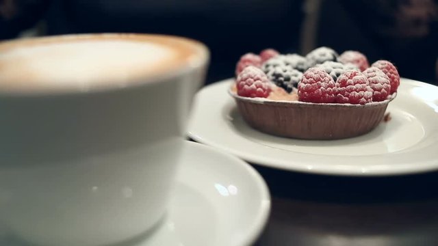 Woman eating dessert and drinking coffee in a cafe, close-up