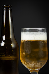 Glass of beer and beer bottle on a wooden background