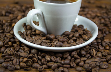 Cup with coffe and coffe beans on wooden background
