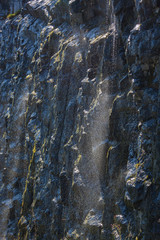 Water spray flowing on wet mossy stones overgrown and glisten in the sun, Norway