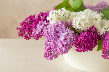Beautiful, purple, pink and white lilac flowers in the big vase on the table. Cozy atmosphere with fresh, fragrant flowers.